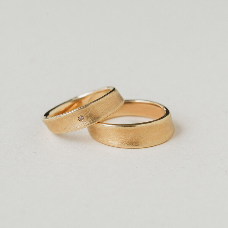 Eheringpaar Konkav aus Gelbgold mit kreismatter Oberfläche und Brillant im Damenring.
