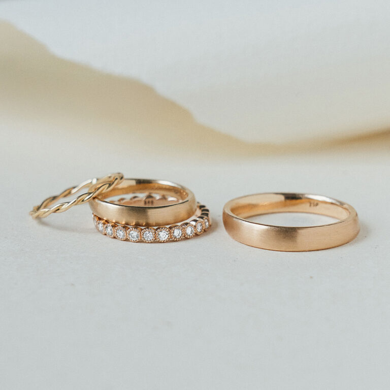 4 goldene Ringe, ein Herrenring und drei Damenringe, die gemeinsam getragen werden können. Einer der Ringe mit filigran gefassten Brillanten