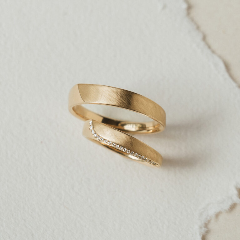 Zwei Eheringe in 585 Gelbgold, der Damenring schmaler mit langer Brillantlinie