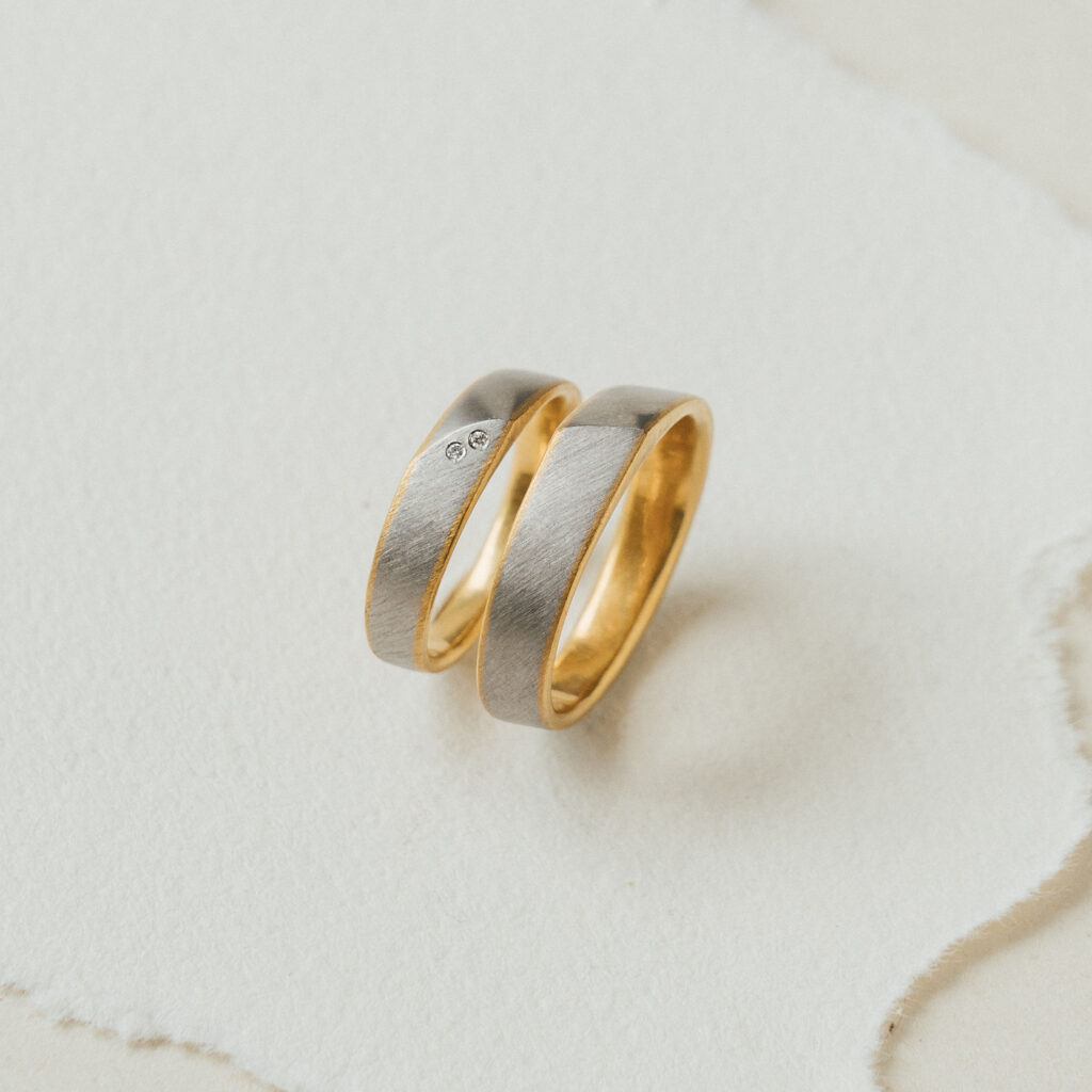 Besonderes Trauringpaar - bicolor, innen Gelbgold, außen in Platin gefertigt. Im Damenring Brillanten.