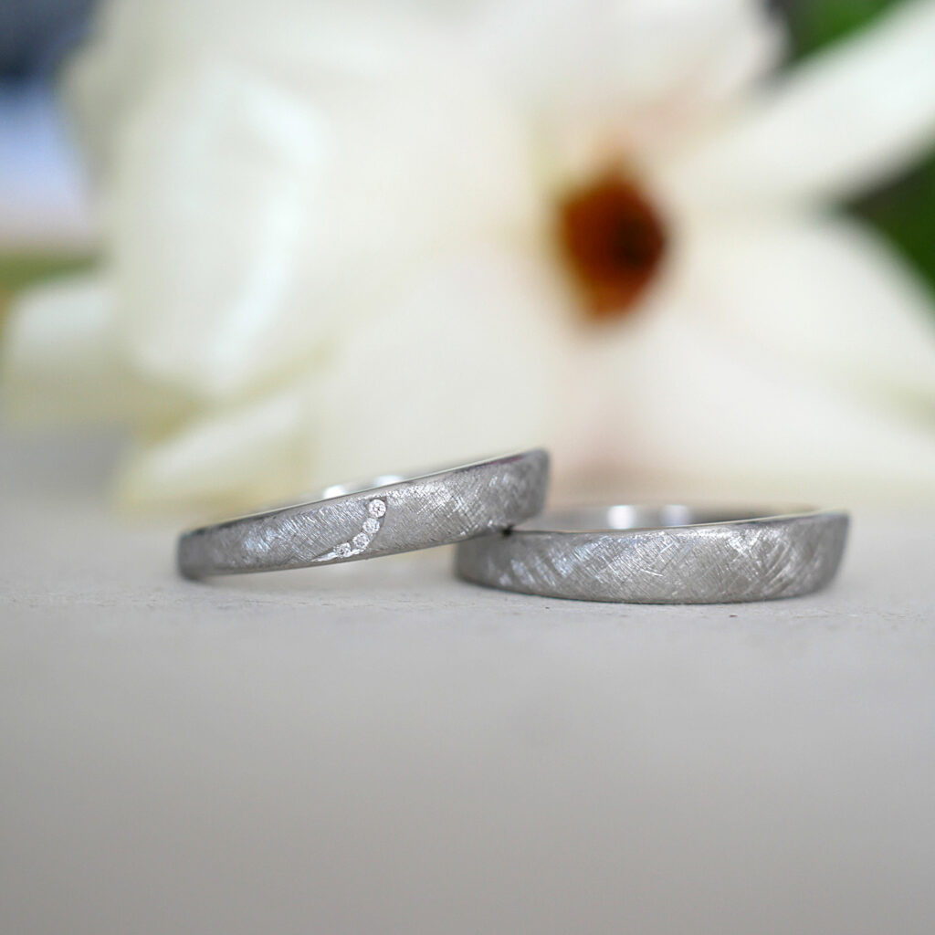 Zwei ergonomische Eheringe aus Platin mit Kreuzmatter Oberfläche und Brillanten im Damenring.