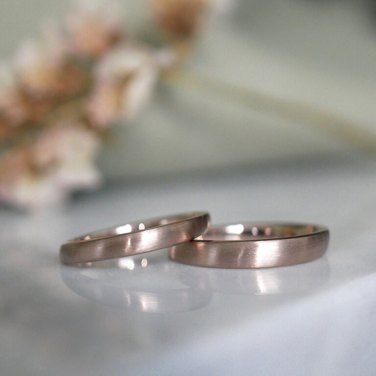 Zwei ergonomische Eheringe aus Roseweißgold mit strichmatter Oberfläche.