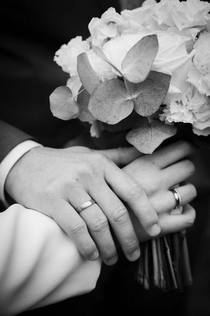 Klassische Trauringe mit Vorsteckring mit 11 Brillanten. Ein schwarz weiß Bild von Händen